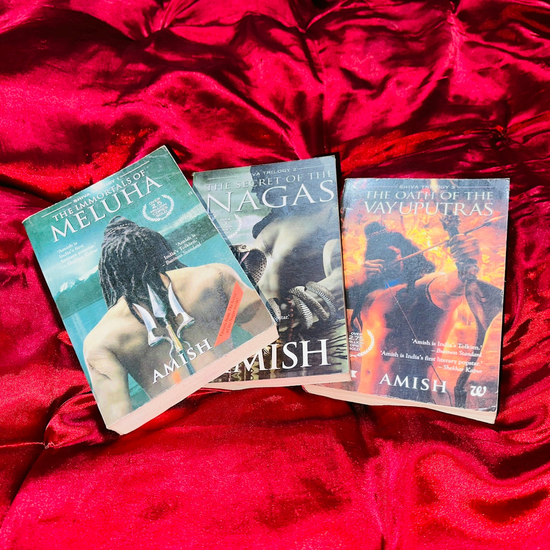 Three books are laying on a red blanket